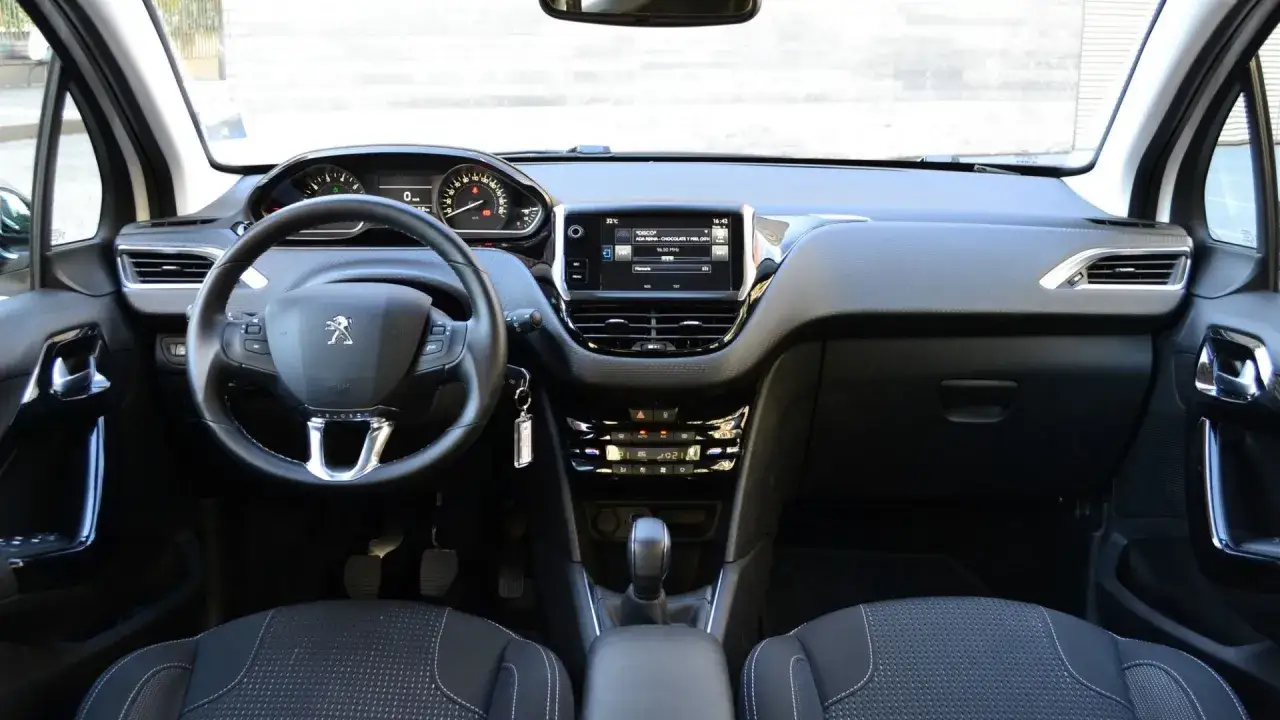 Interno di una Peugeot 208 GPL: volante, cruscotto digitale, schermo touchscreen e cambio automatico.