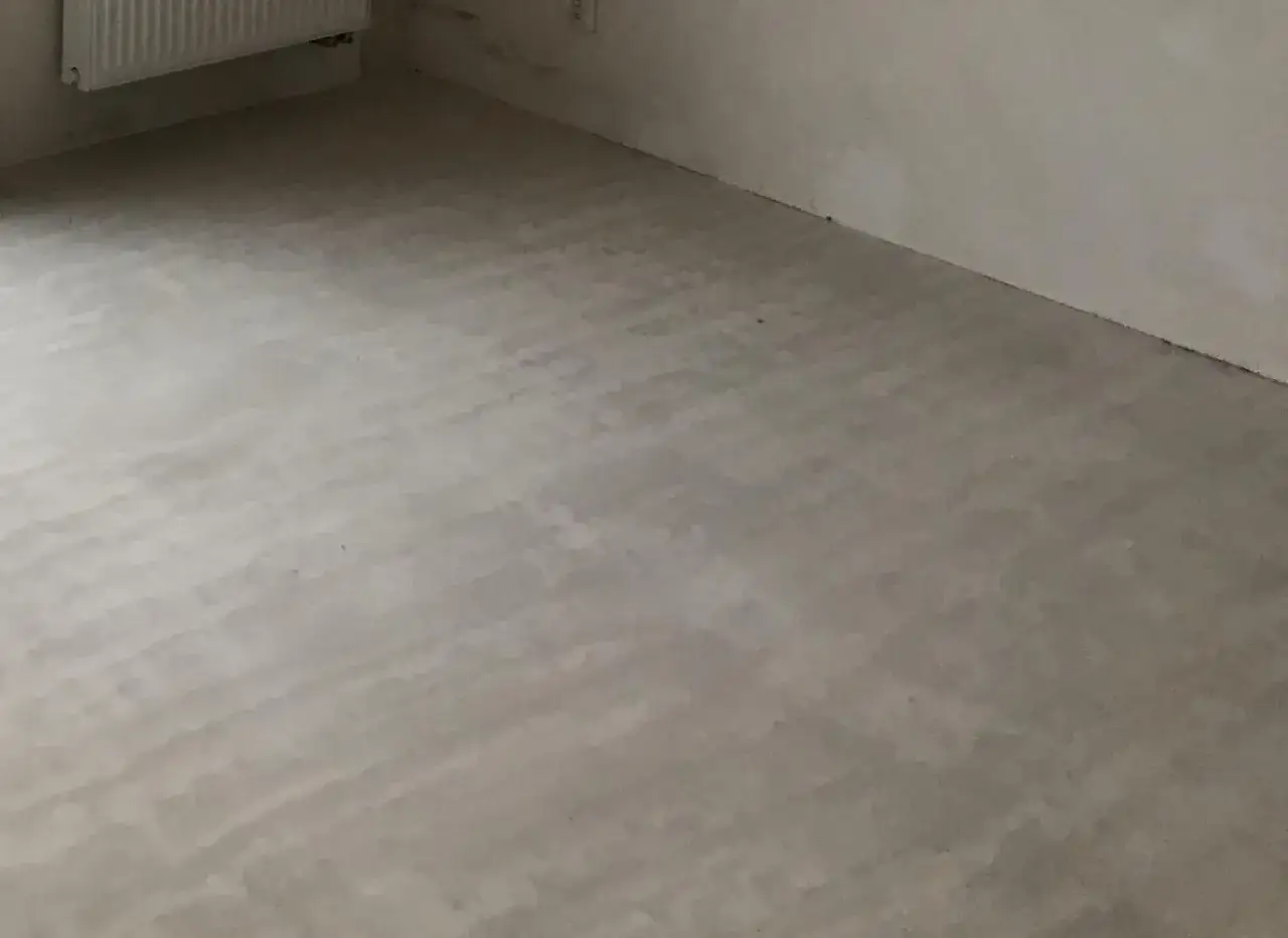 Popękana wylewka samopoziomująca na podłodze, widoczne nierówności i ślady po pracy.