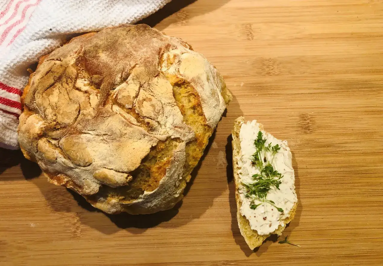 Ein rustikales, frisch gebackenes italienisches Brot Rezept, genial einfach. Daneben eine Scheibe Brot mit Frischkäse und Kresse.