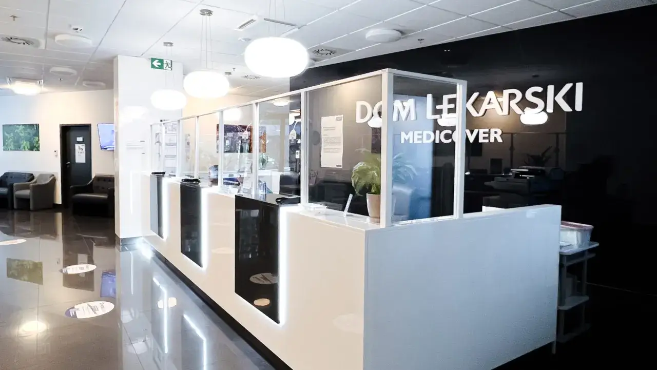 Nowoczesna recepcja w klinice Medicover, z białym ladą, szklanymi przegrodami i logo.
