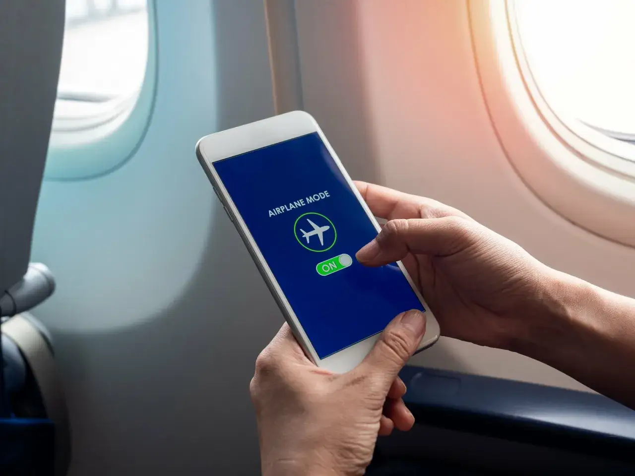 Ręce trzymają telefon z włączonym trybem samolotowym. Czy w samolocie Ryanair jest wifi?