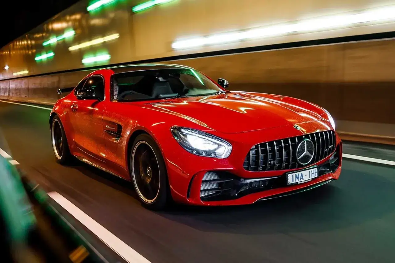Czerwony Mercedes GTR pędzi nocą przez tunel, rozświetlony neonami.