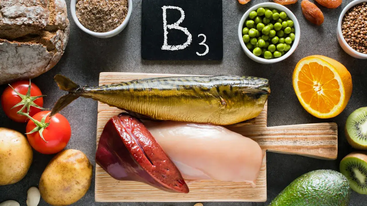 Niacyna co to? Na zdjęciu produkty bogate w witaminę B3: ryba, kurczak, wątróbka, pomidory, ziemniaki, pomarańcza, kiwi, awokado, fasola, orzechy, kasza.