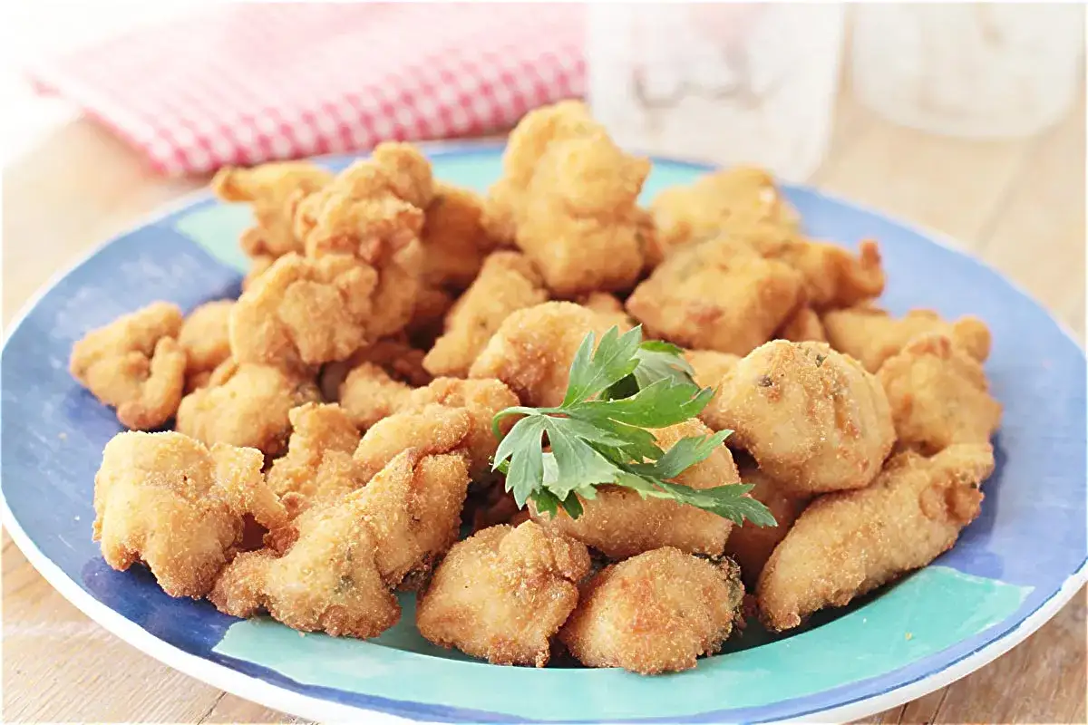 Pinchos de pechugas de pollo empanadas, dorados y crujientes, servidos en un plato azul con perejil fresco.