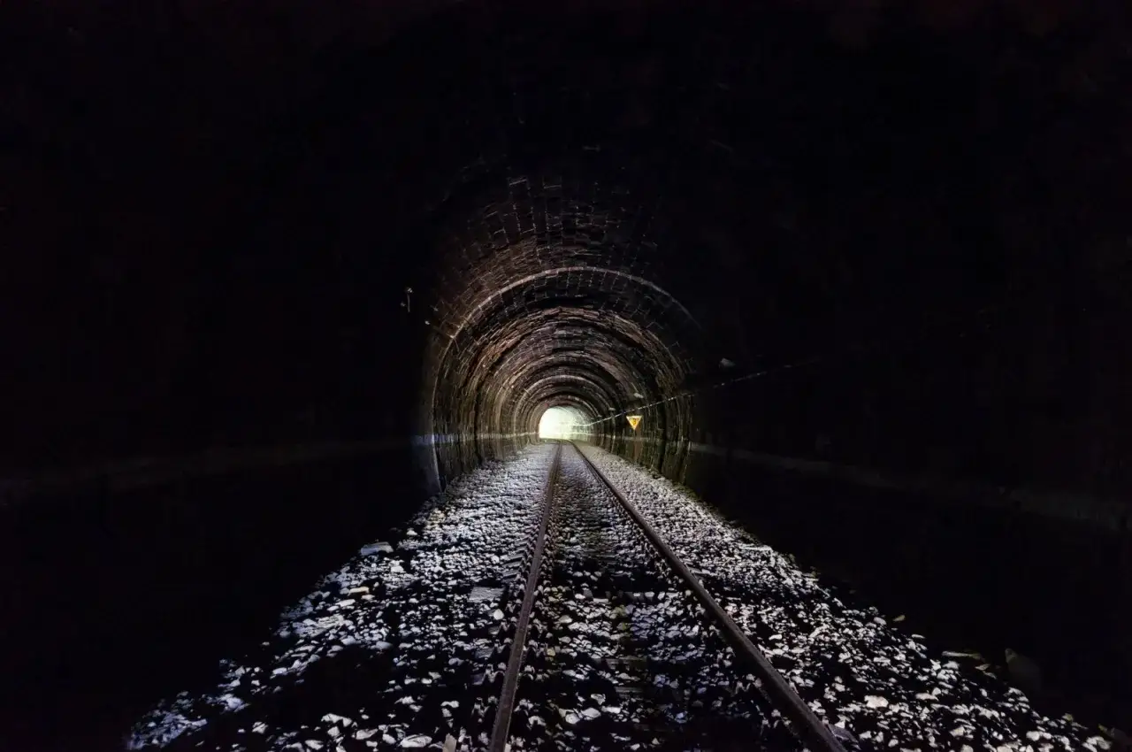 Koleje wąskotorowe na przełęczy łupkowskiej wiodą przez mroczny tunel. Światło na końcu zaprasza do podróży.