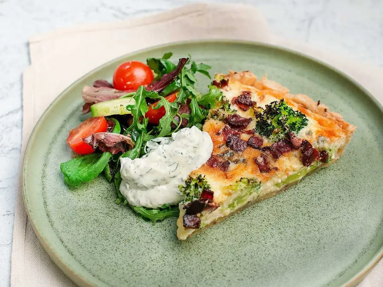 En bit ost och broccolipaj med knaperstekt bacon, serverad med en fräsch sallad och en klick vitlökssås.