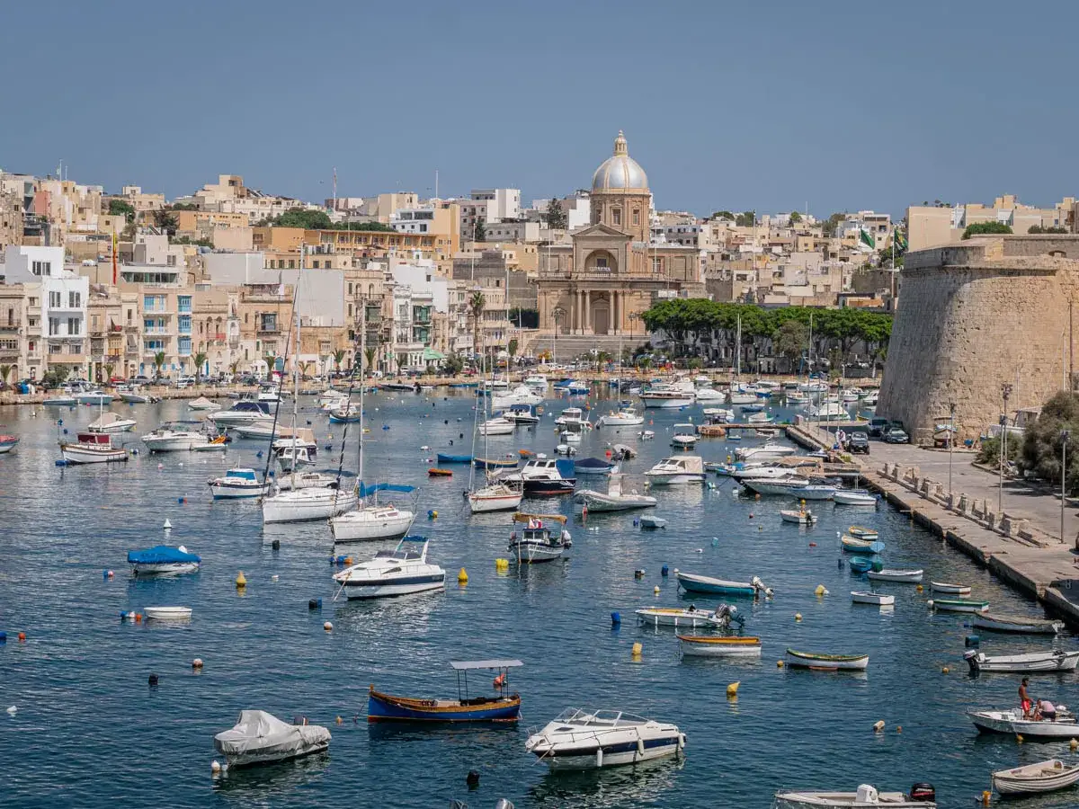 Malta: zatoka pełna łodzi, z kościołem i fortyfikacjami w tle. Idealne miejsce, by zobaczyć, co oferuje Malta.