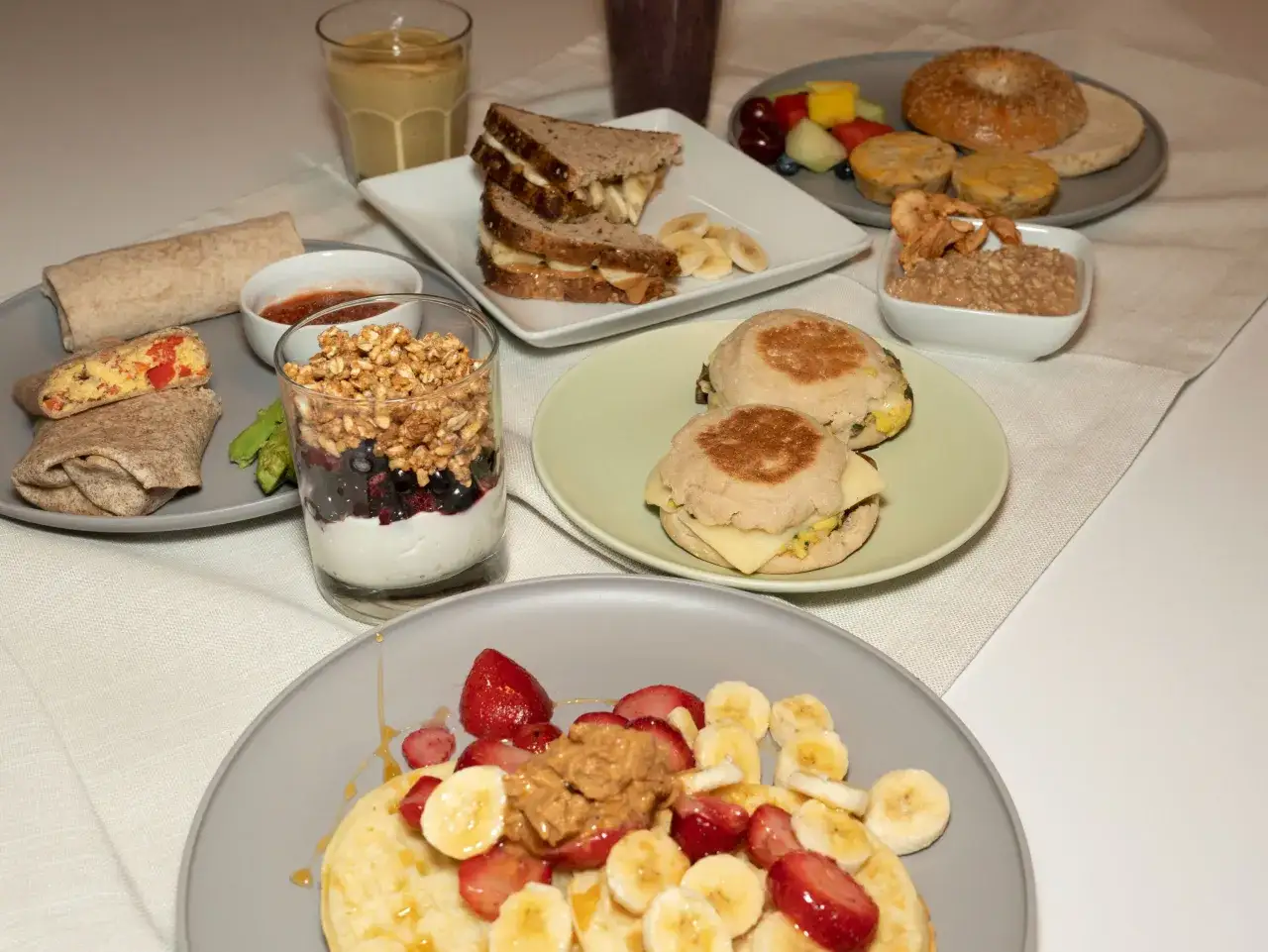 Petit-d&eacute;jeuner vari&eacute; : pancakes aux fruits, burritos, sandwichs, yaourt et granola. Id&eacute;al pour savoir quoi manger avant de courir le matin.