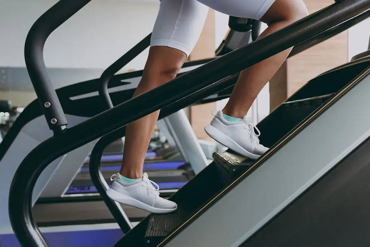 Beine auf einem Stepper, der den Kalorienverbrauch beim Training steigert.