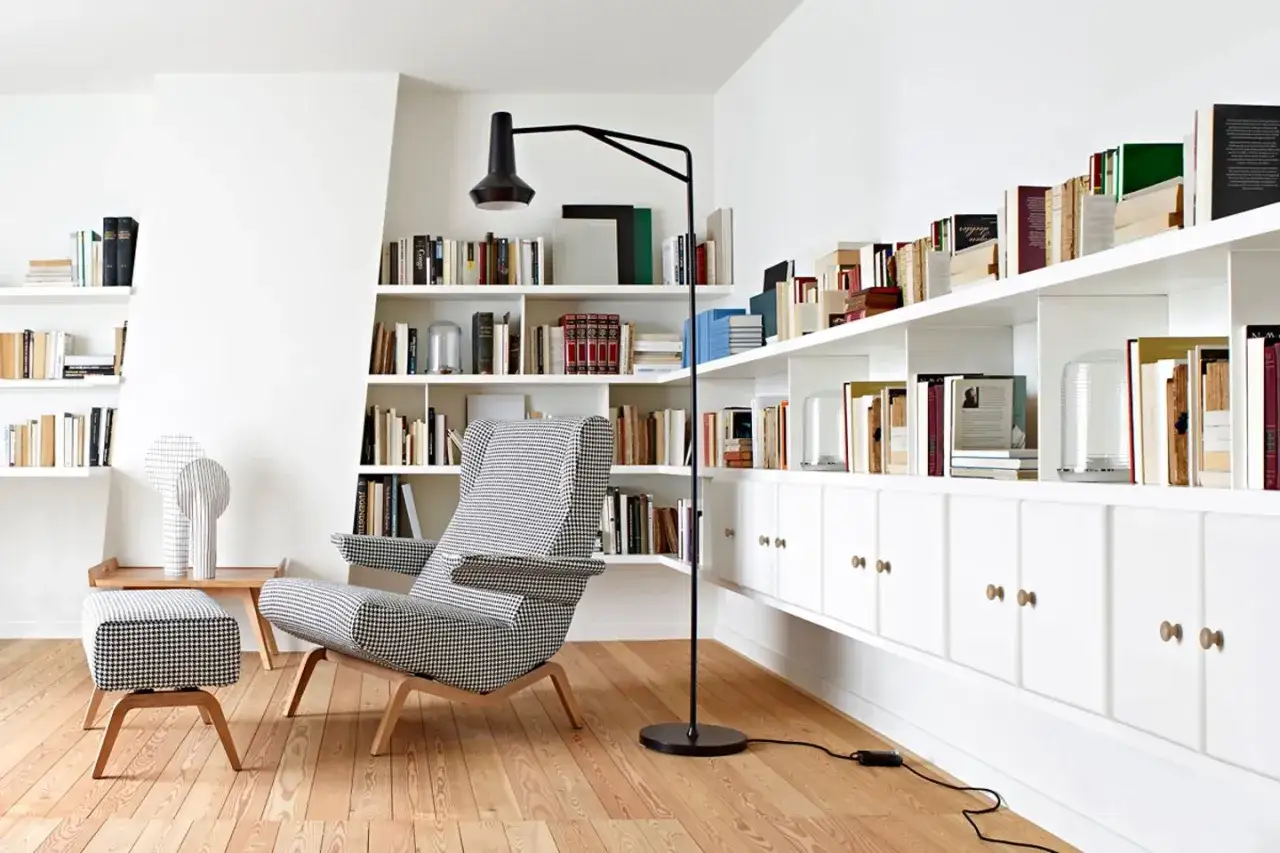 Gemütliche leseecke klein mit kariertem Sessel und Hocker, umgeben von Bücherregalen.