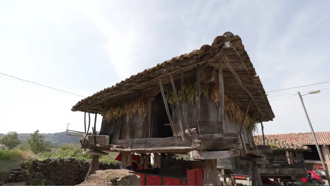 Un horreo asturiano de madera, con ristras de pimientos secándose, se alza sobre pilares de piedra.