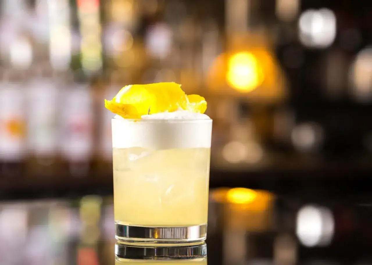 Orzeźwiający drink z pianką i skórką cytryny. Idealny przepis na vodka sour.