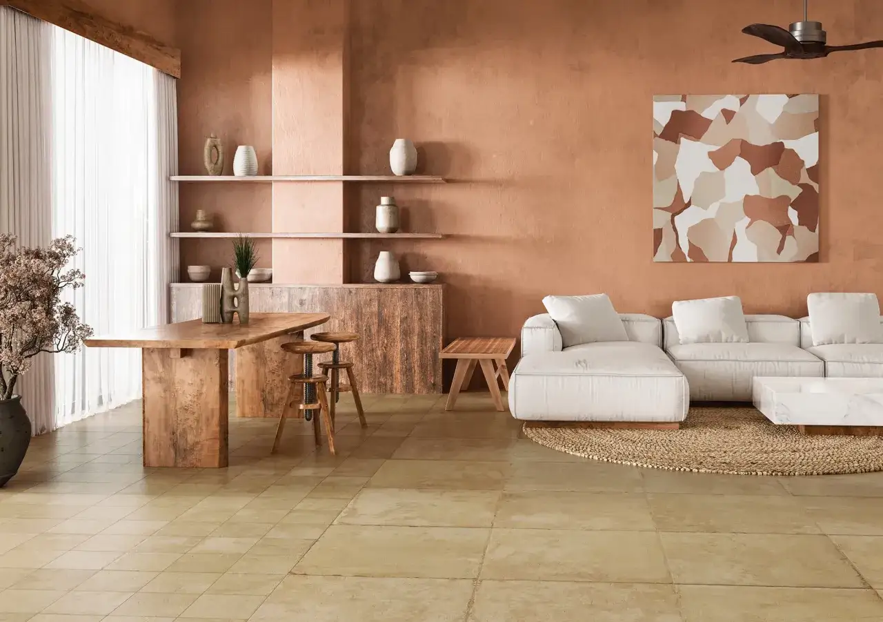 Un c&aacute;lido sal&oacute;n con suelo terracota interior, paredes en tonos tierra, muebles de madera r&uacute;stica y un sof&aacute; blanco.