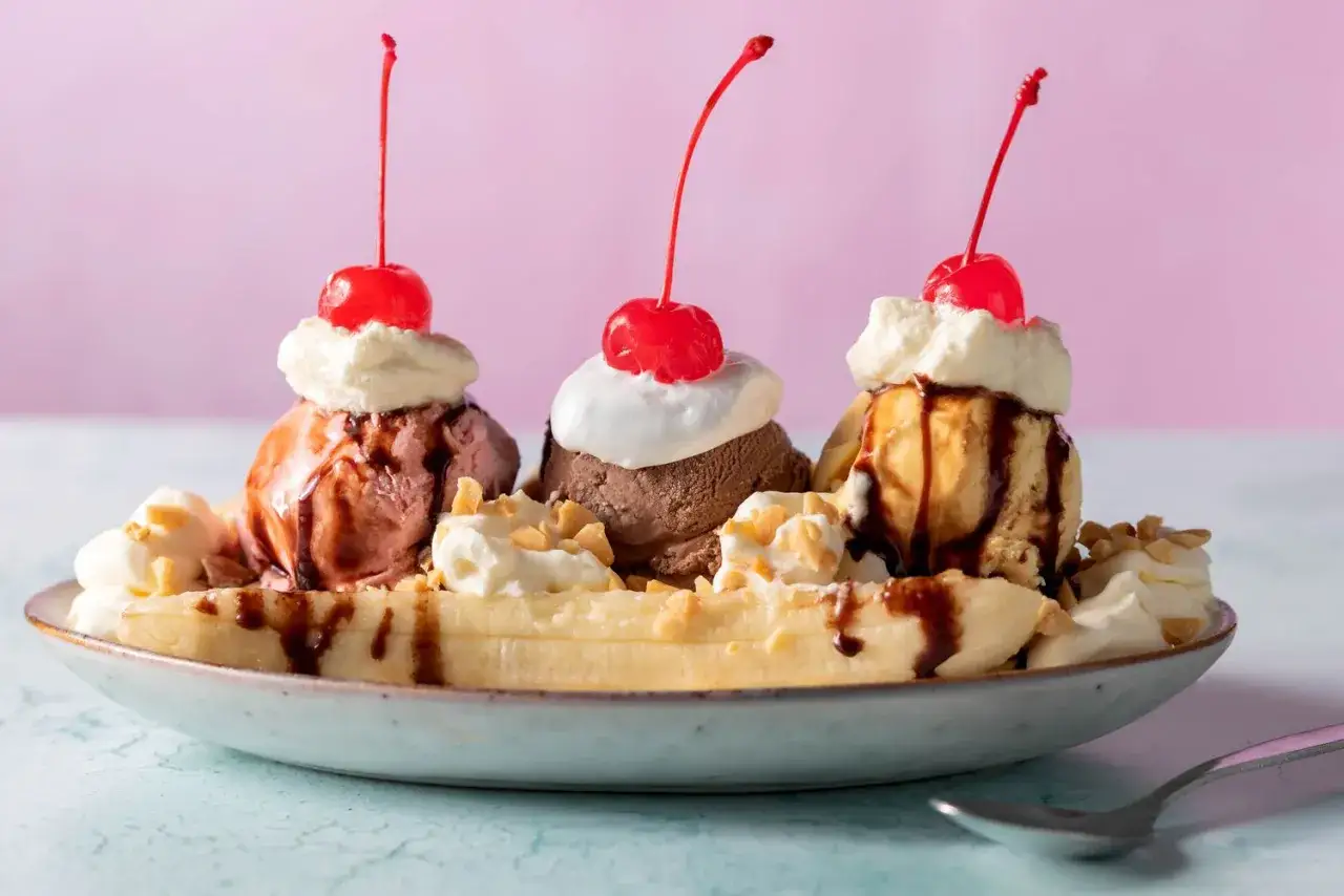 Ein klassisches Banana Split Eis mit drei Kugeln Eis, Sahne, Kirschen und Schokoladensauce auf einer Banane.