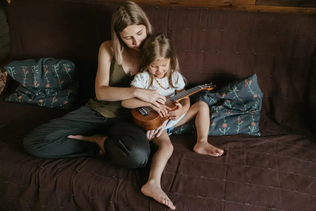 Mama uczy c&oacute;rkę grać na ukulele, wsp&oacute;lnie budując relacje.