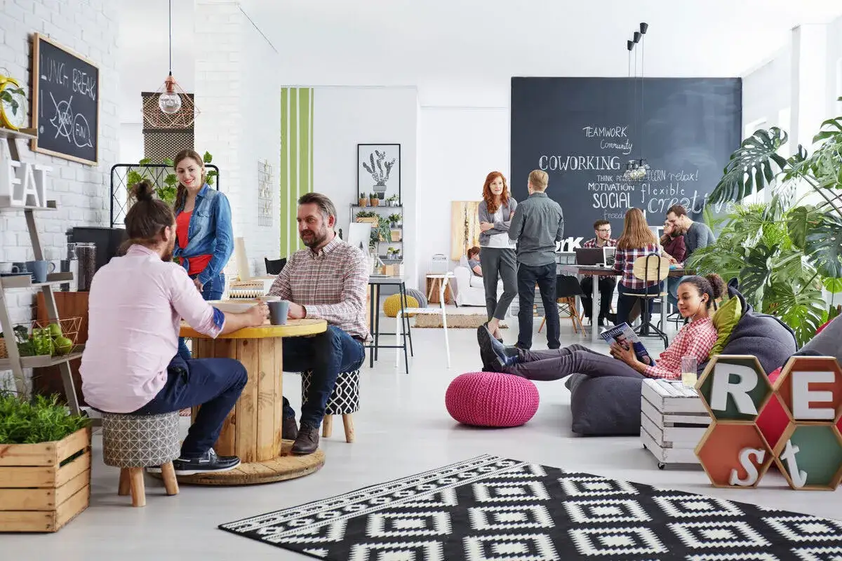 Menschen treffen sich in einem hellen, modernen Coworking-Space. Dies ist ein Beispiel für wohnen in der zukunft, wo Arbeit und Gemeinschaft verschmelzen.