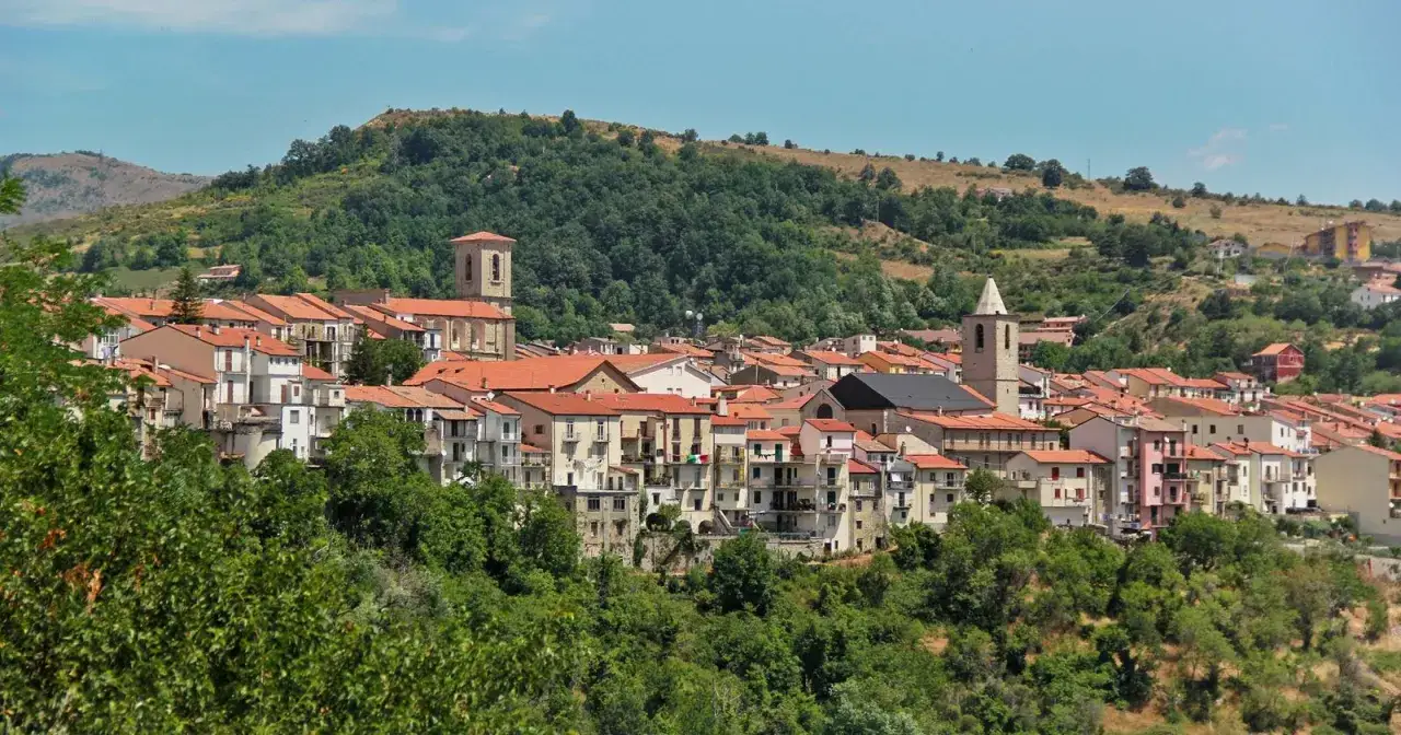 Un pittoresco paese delle campane Molise, con tetti rossi e chiese che svettano tra le colline verdi.