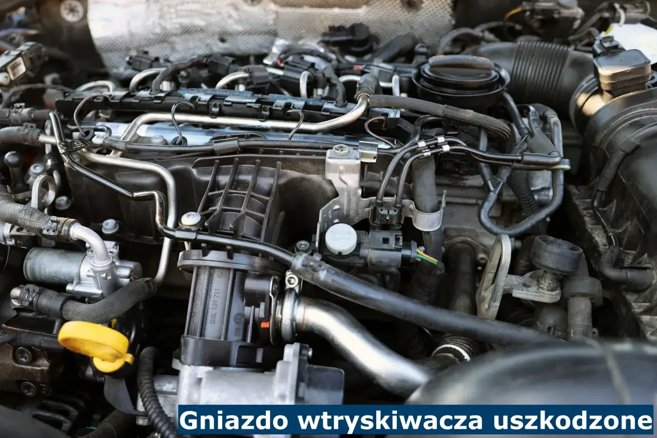 Widok silnika samochodowego z widocznym mokrym gniazdkiem wtryskiwacza, które wymaga naprawy.