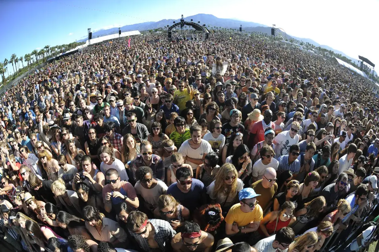 Tłum ludzi na festiwalu Coachella, gdzie to się odbywa? Słońce, palmy i góry w tle.