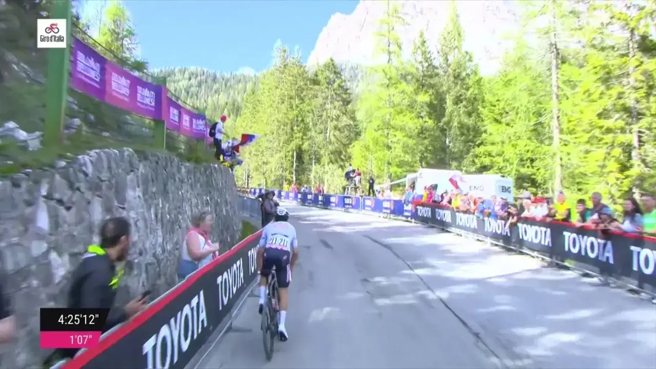 Kolarz jedzie w Giro d'Italia wśród kibiców i górskich krajobrazów.