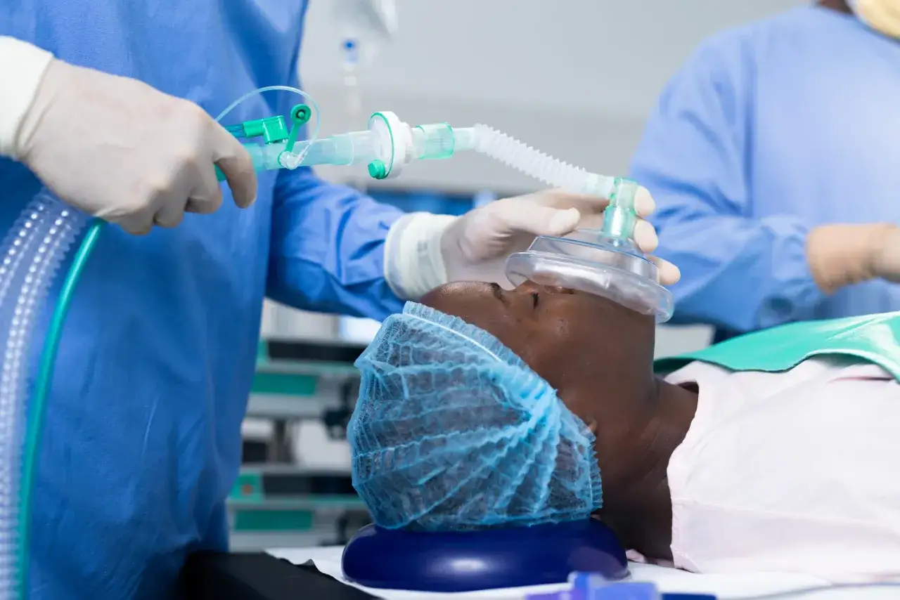 Paciente recibe anestesia general para extracción de muelas del juicio. Un profesional médico ajusta la mascarilla de ventilación.