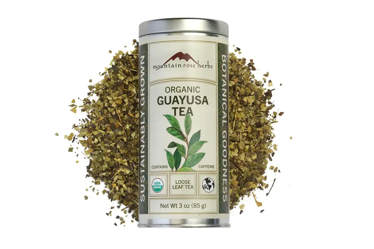 Puszka organicznej herbaty guayusa, otoczona liśćmi. Zastanawiasz się nad guayusa skutki uboczne? Ta herbata zawiera kofeinę.