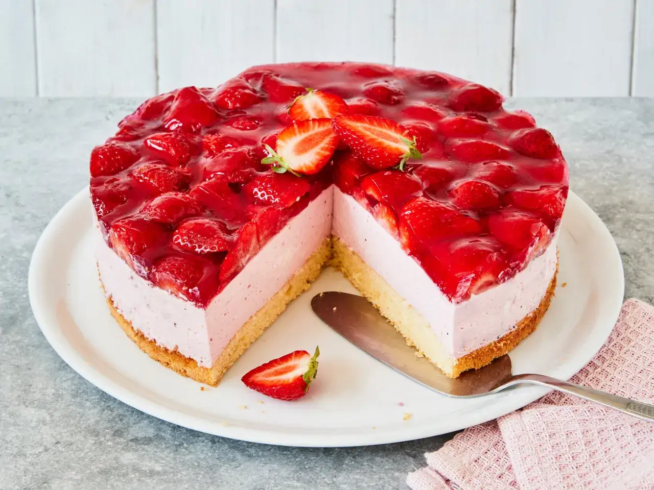 Saftige Erdbeer Mascarpone Torte mit frischen Erdbeeren und Tortenguss, auf einem wei&szlig;en Teller, bereit zum Servieren.