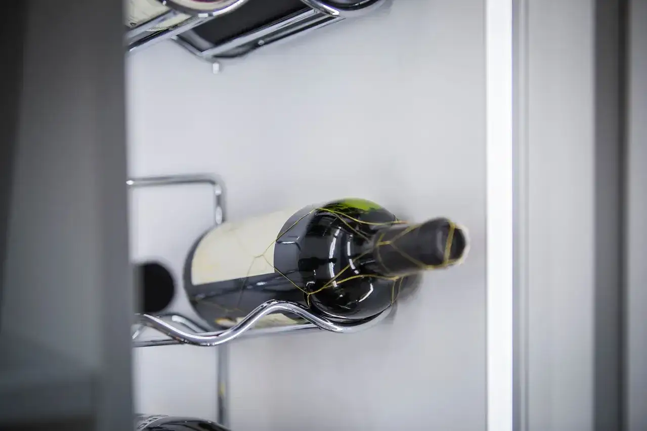Offener Rotwein lagern: Eine Flasche Rotwein liegt auf einem Chrom-Gestell in einem Kühlschrank.