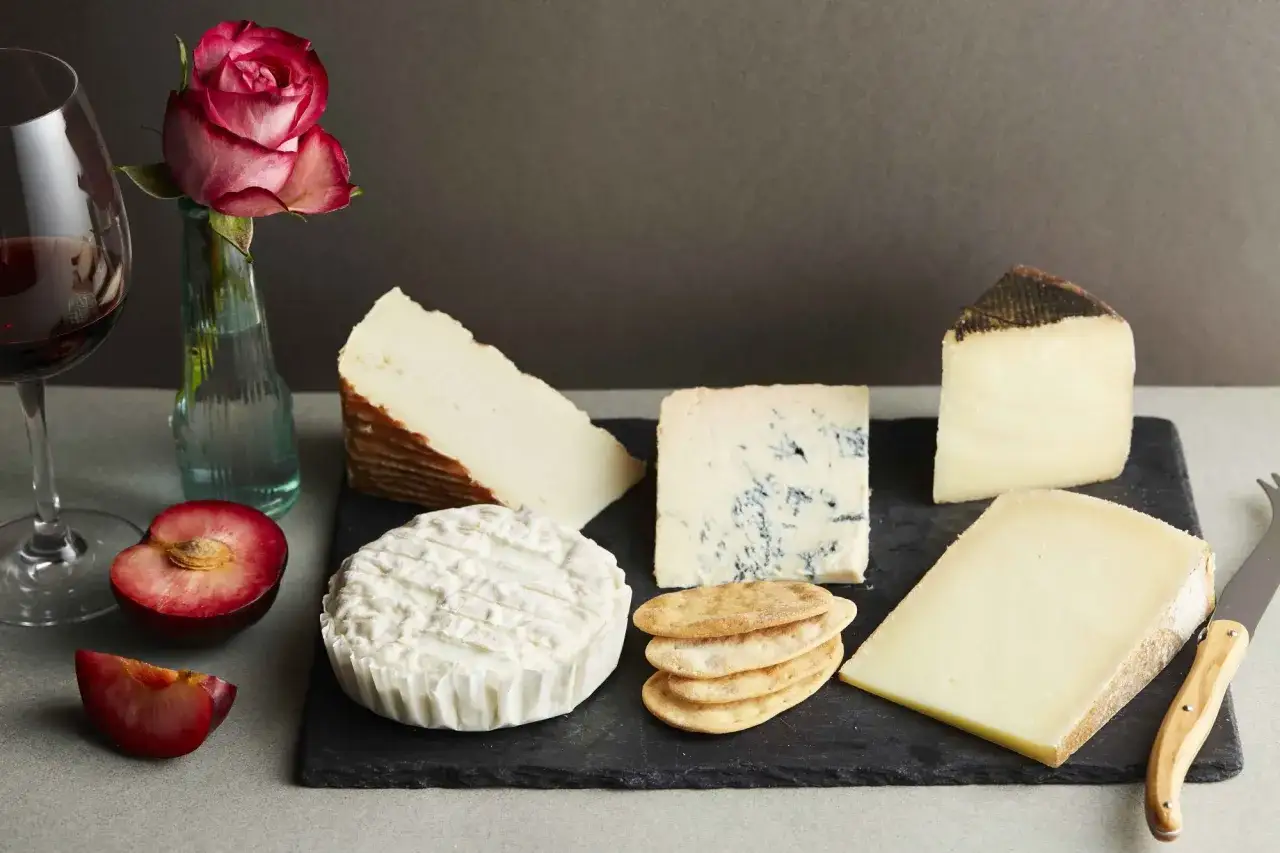 En h&auml;rlig ostbricka med olika sorters italiensk ost, plommon, kex, ett glas r&ouml;dvin och en ros.