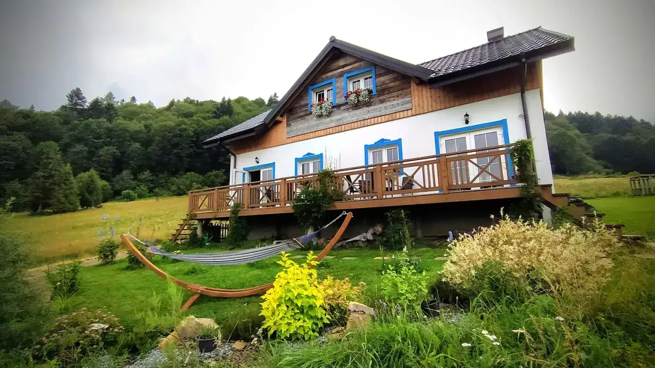 Dom z drewnianym tarasem i hamakiem, otoczony zielenią. Idealne miejsce, by odpocząć i zastanowić się, gdzie w Bieszczady.