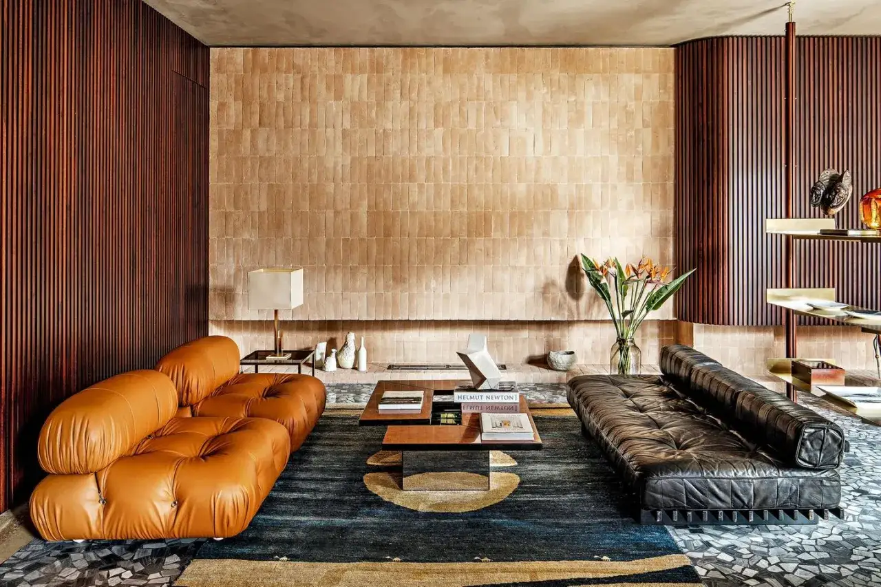 Stilvolles **mid century living room** mit cognacfarbenem Ledersofa, schwarzem Ledersofa, Holzwandverkleidung und Kachelofen.