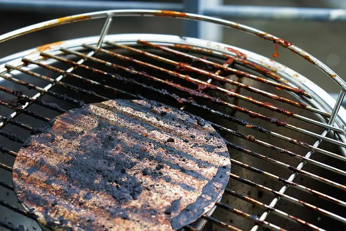 Ein eingebrannter Grillrost mit hartn&auml;ckigen R&uuml;ckst&auml;nden, der dringend eine Reinigung ben&ouml;tigt.