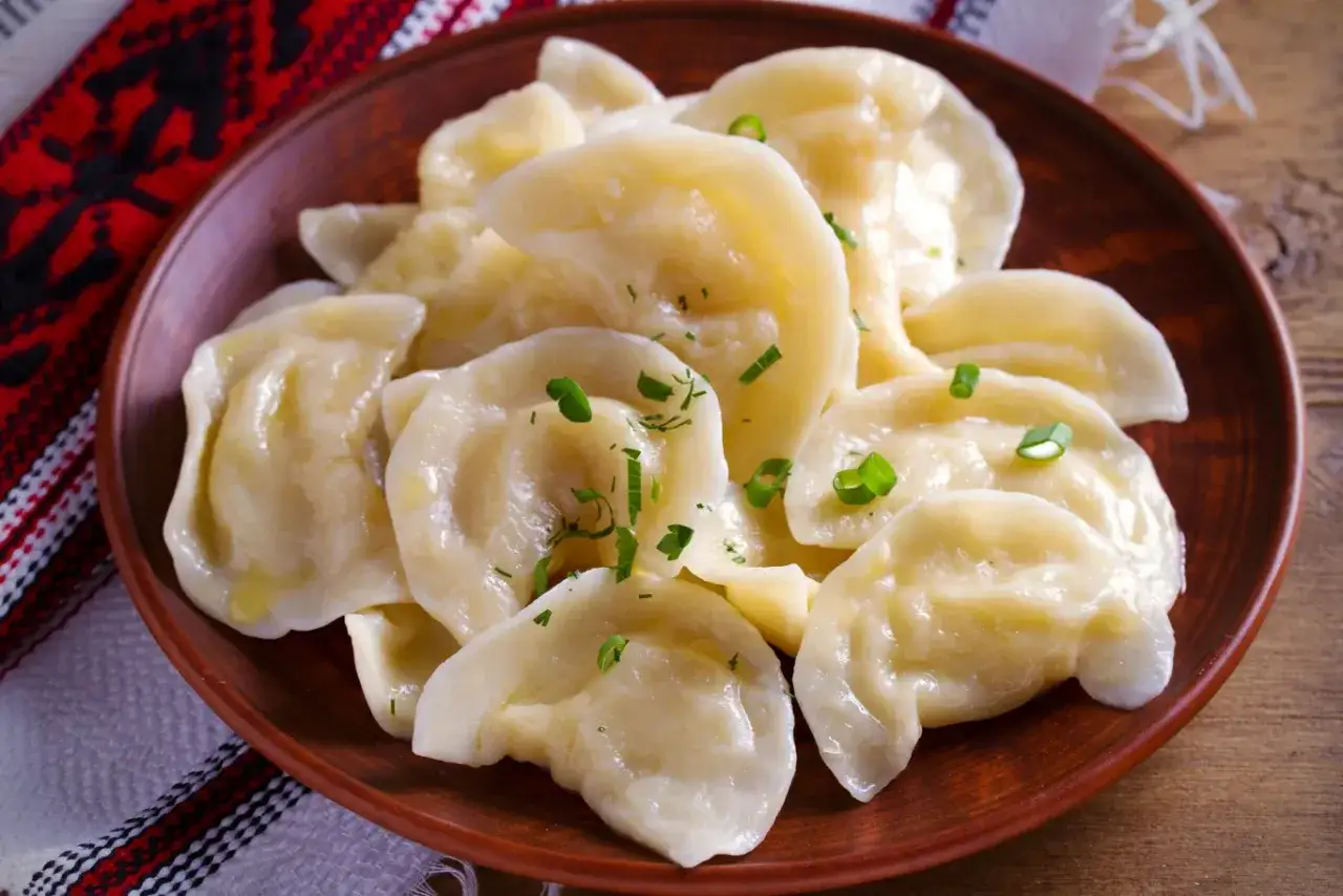 Pyszne, gorące pierogi z serem, posypane szczypiorkiem. Idealne, gdy wiesz, jak gotować pierogi, by były tak apetyczne.