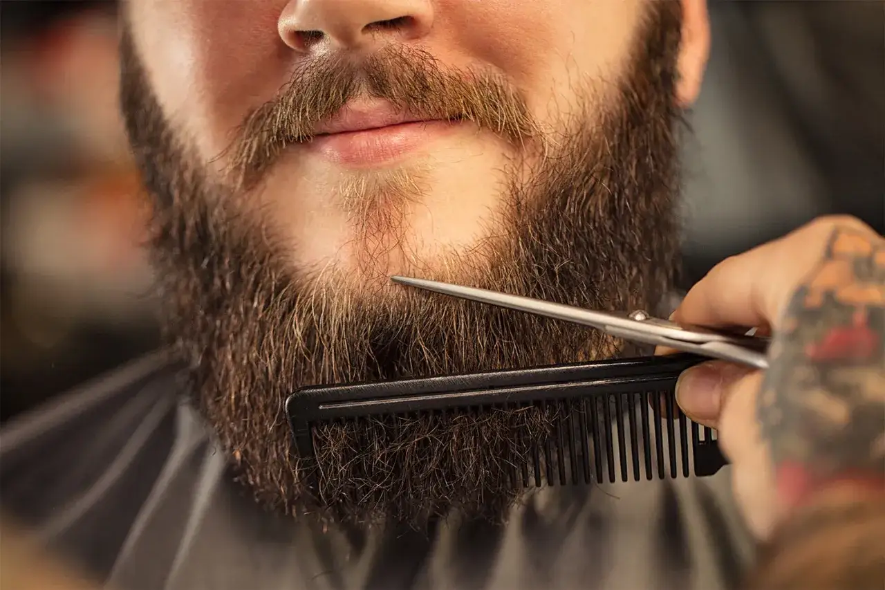 Stylista przycina brodę grzebieniem i nożyczkami. Dowiedz się, jak zapuścić brodę i nadać jej idealny kształt.