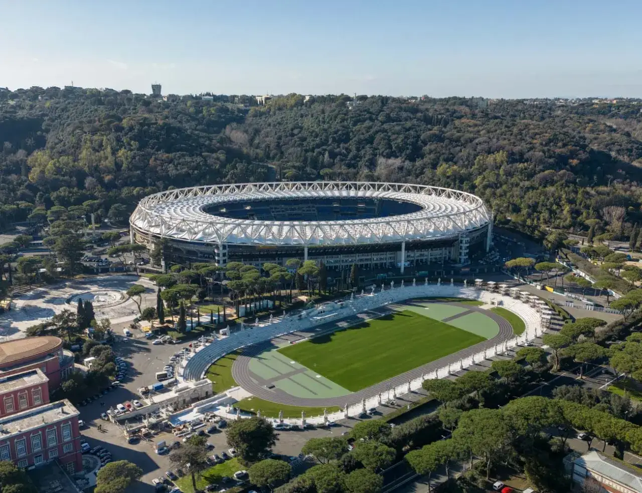 Stadion w Rzymie, otoczony zielenią, z bieżnią i boiskiem. Widok z lotu ptaka na architekturę i otoczenie.