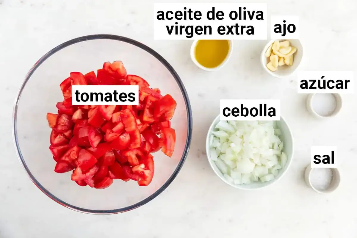 Ingredientes para una deliciosa salsa de tomate: tomates picados, cebolla, ajo, aceite de oliva virgen extra, az&uacute;car y sal.