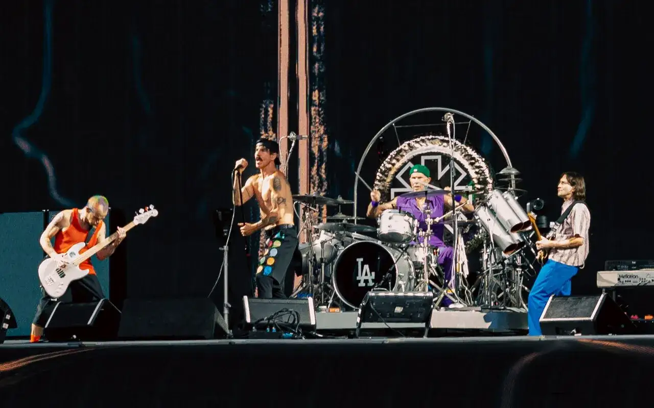 Les membres de Red Hot Chili Peppers en pleine performance. Flea à la basse, Anthony Kiedis au chant, Chad Smith à la batterie et John Frusciante à la guitare.