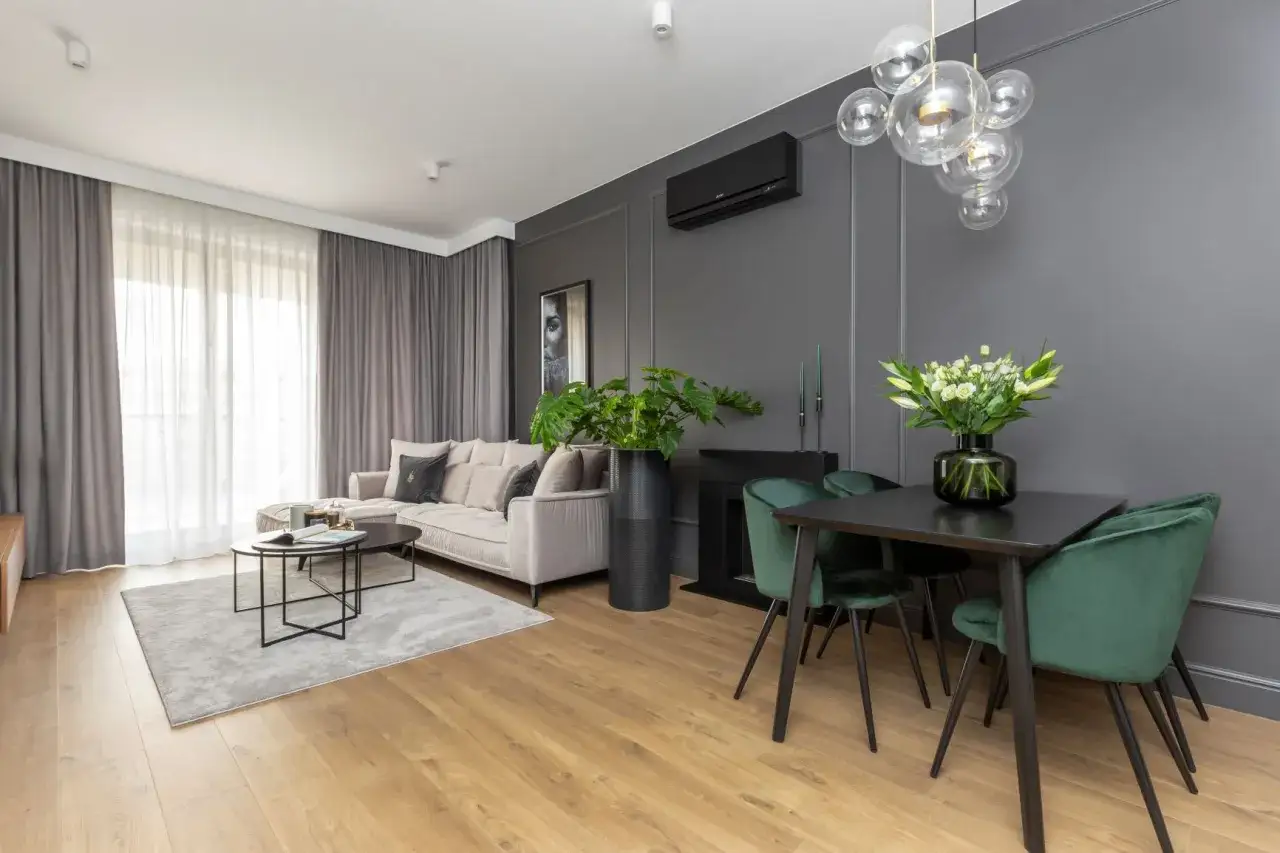 Nowoczesny salon z szarą kanapą i dywanem. Zielone krzesła przy czarnym stole pokazują, jaki kolor pasuje do szarego, tworząc elegancką całość.