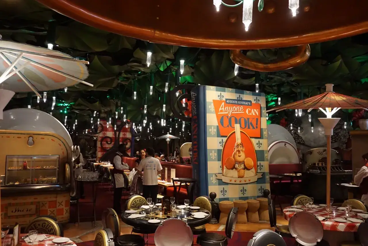 Im Inneren eines **Ratatouille Restaurants in Paris** steht ein riesiges Kochbuch mit Auguste Gusteau. Tische sind für Gäste gedeckt.