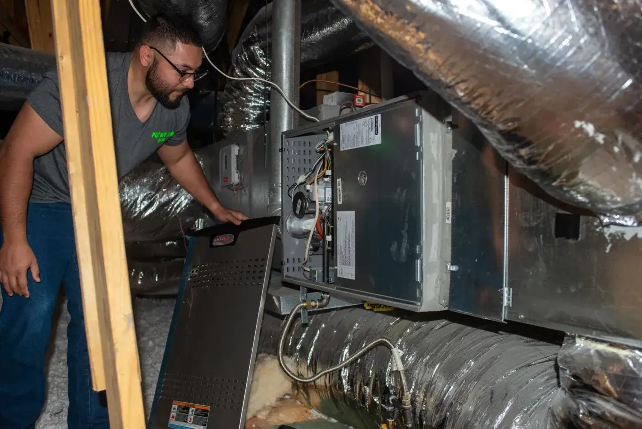 Tecnico controlla la pompa di calore nel sottotetto, tra i condotti isolati.