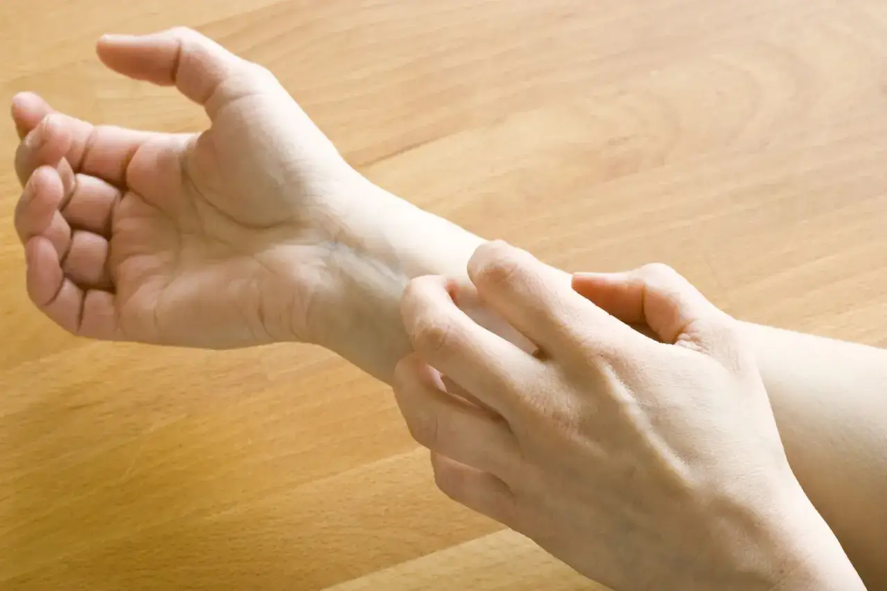 Mano che si gratta il polso, possibile sintomo di prurito avambracci cause.