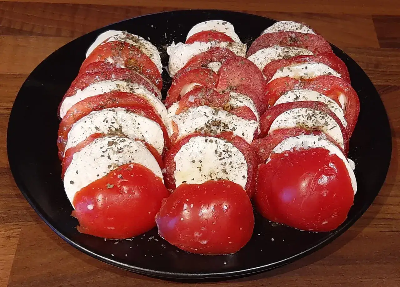 Salade Caprese pr&ecirc;te &agrave; d&eacute;guster, une recette simple avec mozzarella, tomates et herbes.