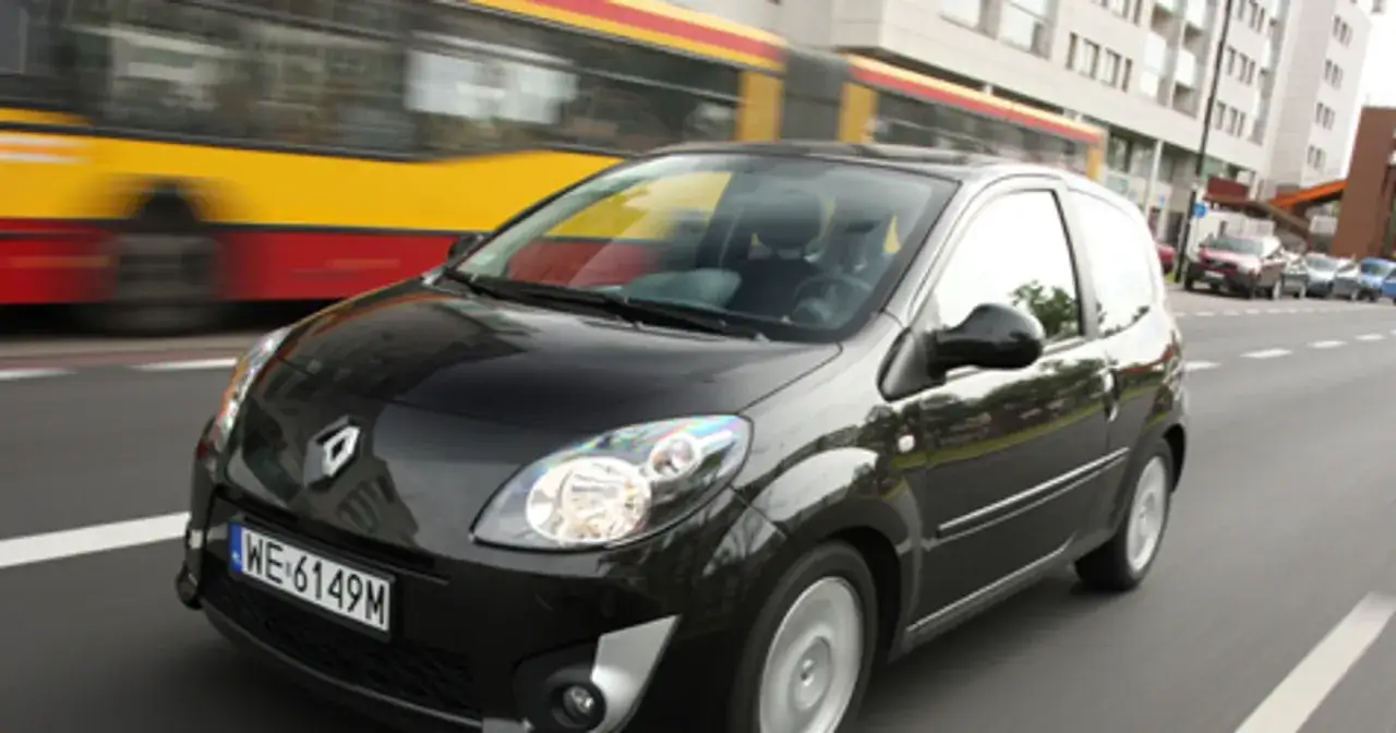 Czarny Renault Twingo 2 jedzie ulicą, mijając tramwaj.