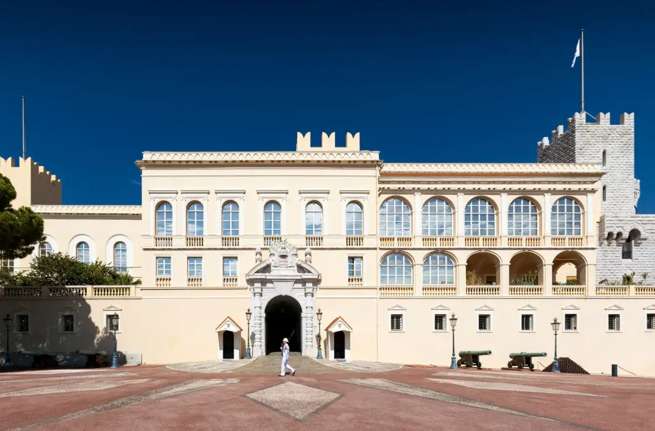 Palacio del Príncipe de Mónaco, un lugar imperdible que ver en Mónaco. Guardia con uniforme blanco camina frente a la entrada principal.