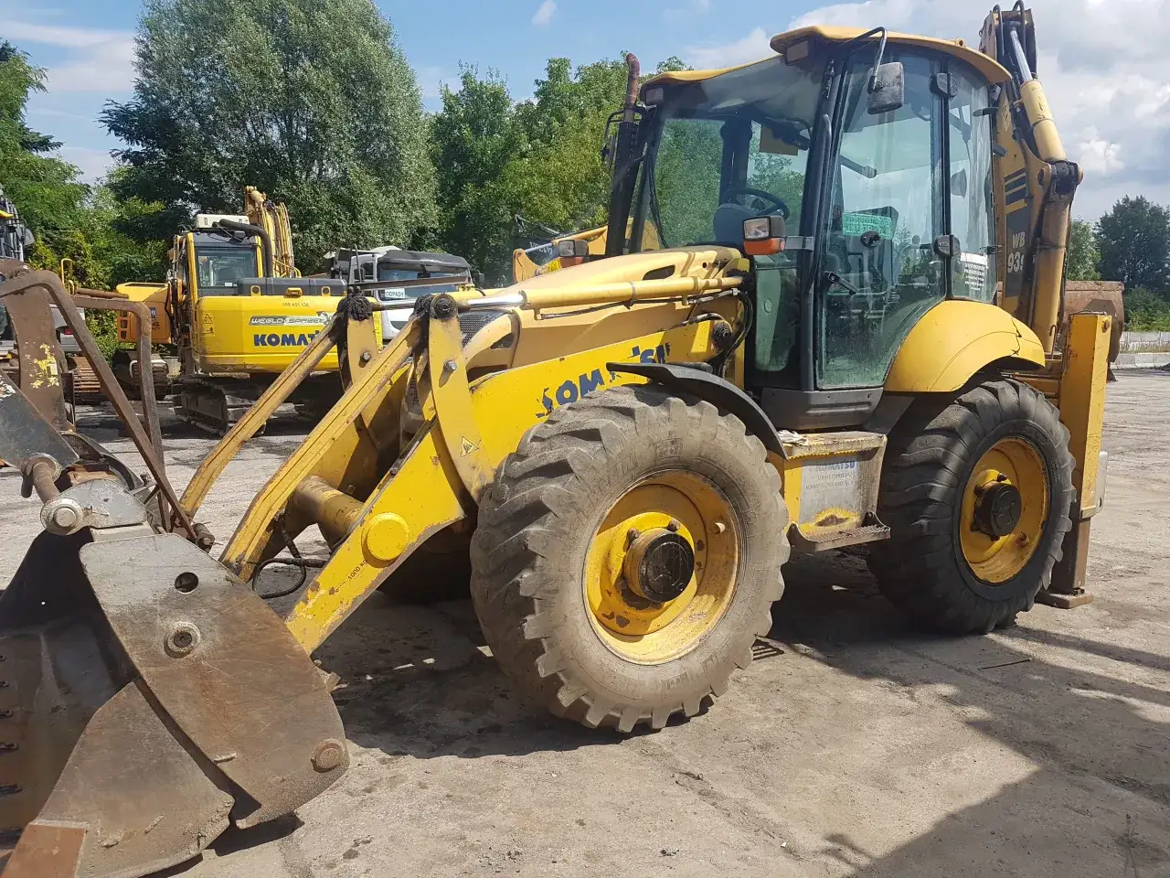 Żółta koparka kołowa Komatsu z dużym łyżką i masywnymi oponami stoi na placu budowy.