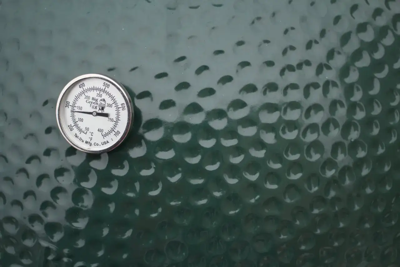 Thermom&egrave;tre sur un kamado vert, indiquant la temp&eacute;rature pour une cuisson parfaite.