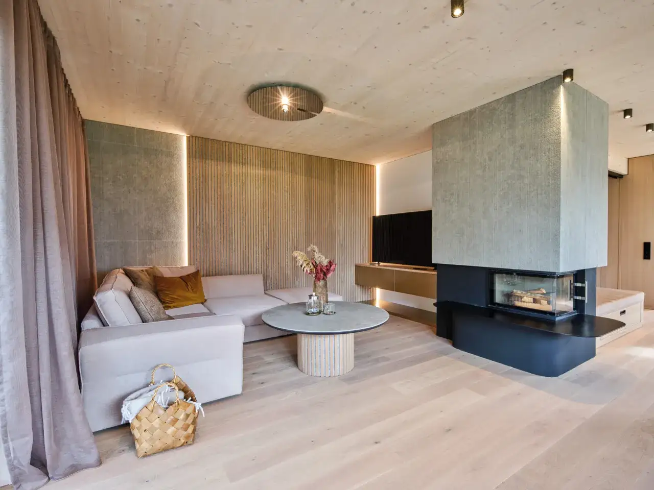 Ein **helles Wohnzimmer** mit gemütlicher Sitzecke, modernem Kamin und Holzakzenten.