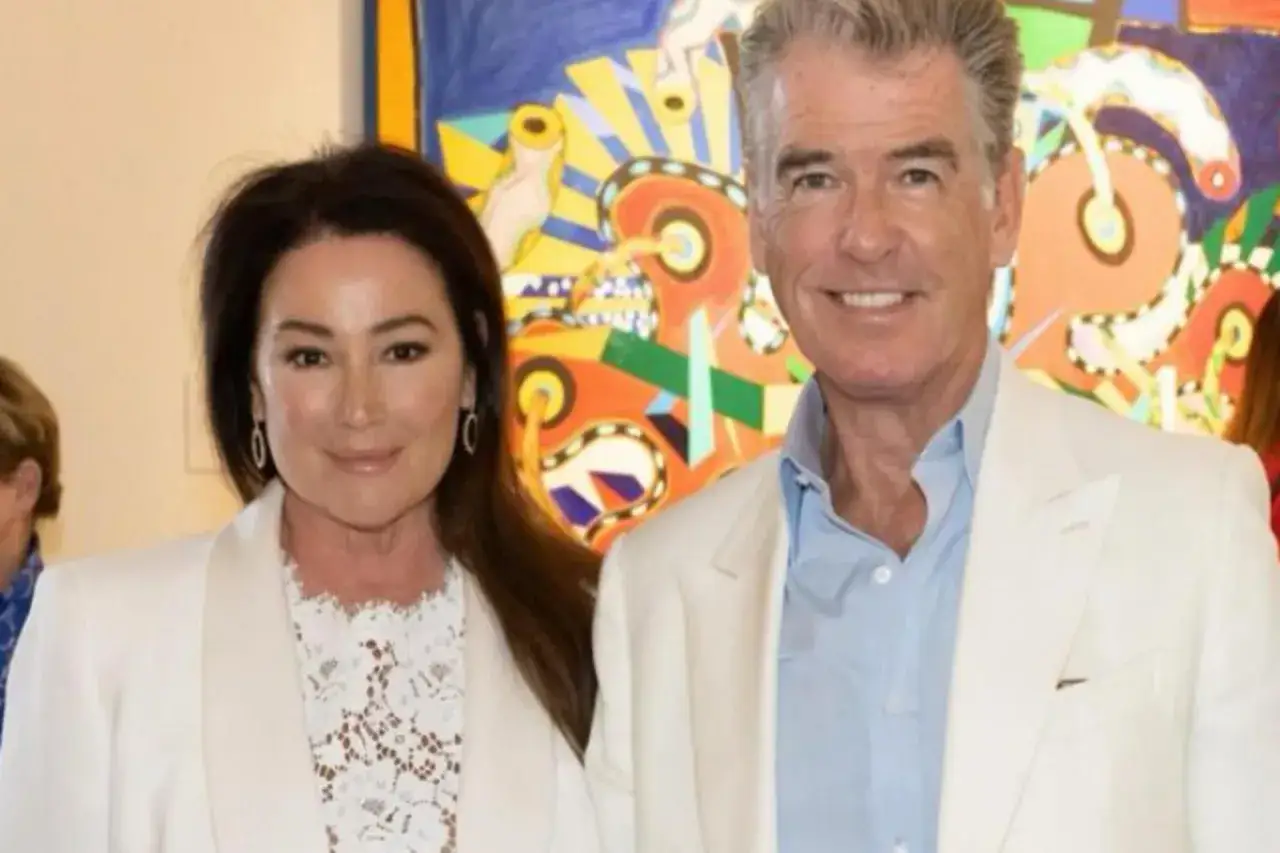 Pierce Brosnan z żoną Keely Shaye Smith, uśmiechnięci na tle kolorowego obrazu.