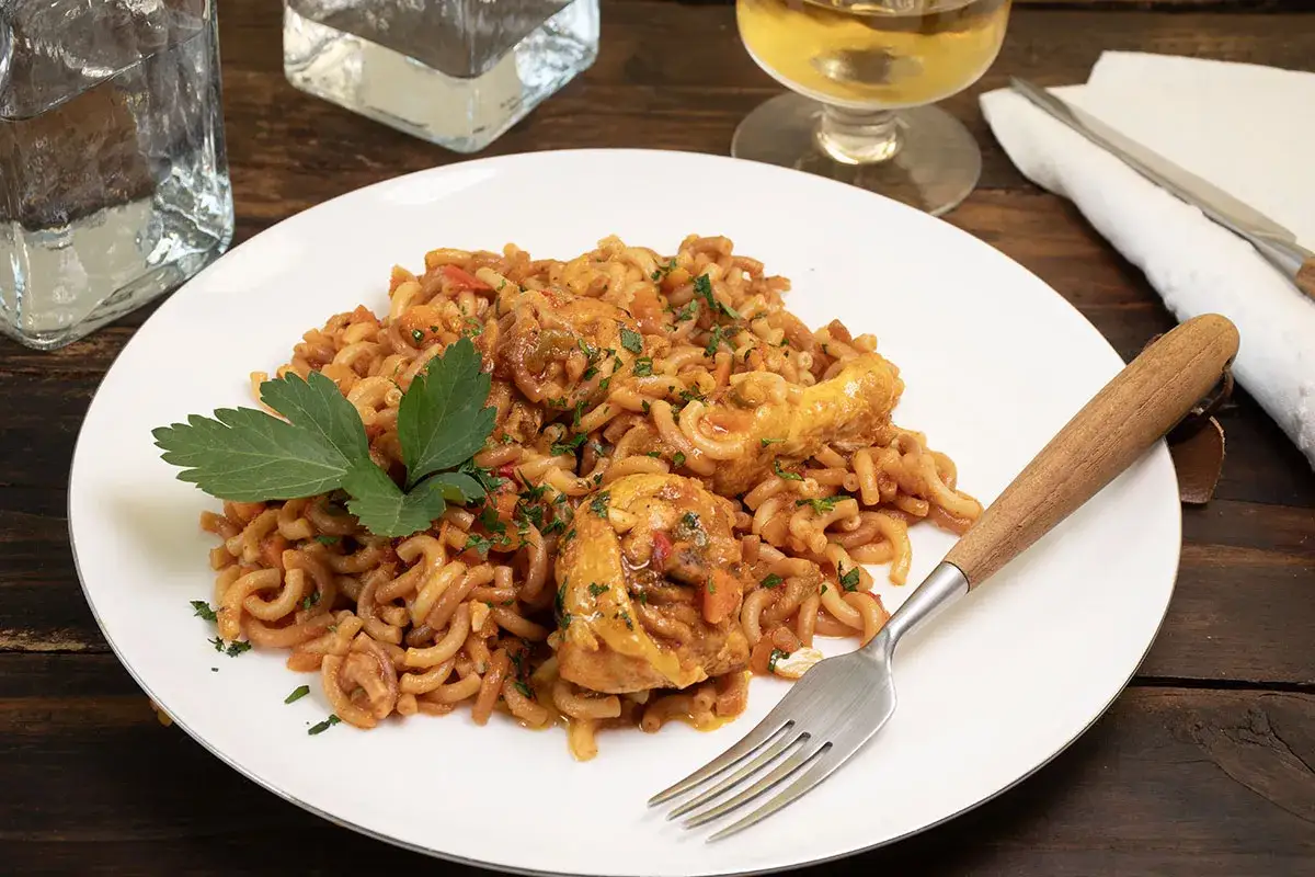 Fideu&agrave; de pollo servida en plato blanco, con trozos de pollo y fideos en salsa. Decorada con perejil fresco.