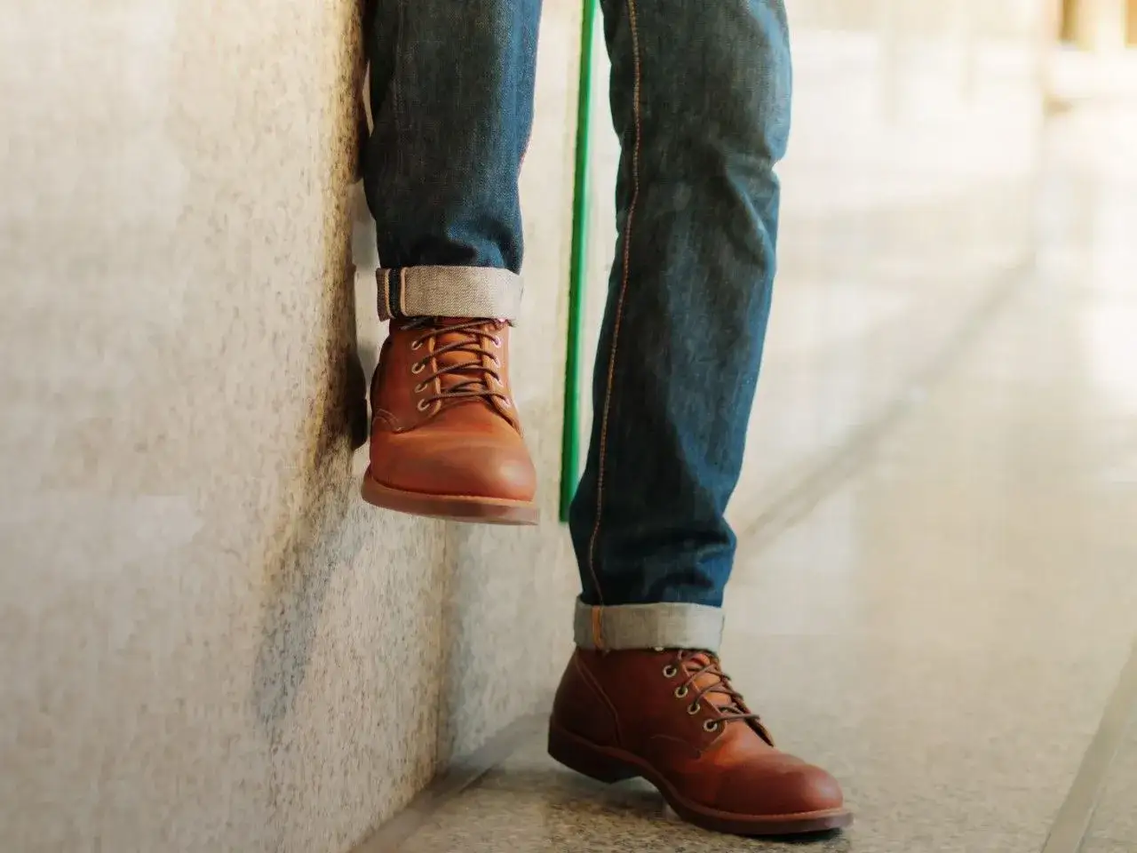Elegancko podwinięte nogawki jeansów i brązowe buty. Stylowy sposób, jak podwinąć spodnie, by podkreślić obuwie.